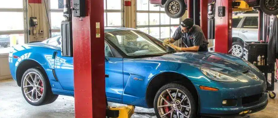 Technician repairing a car windshield, a common trigger for ADAS recalibration