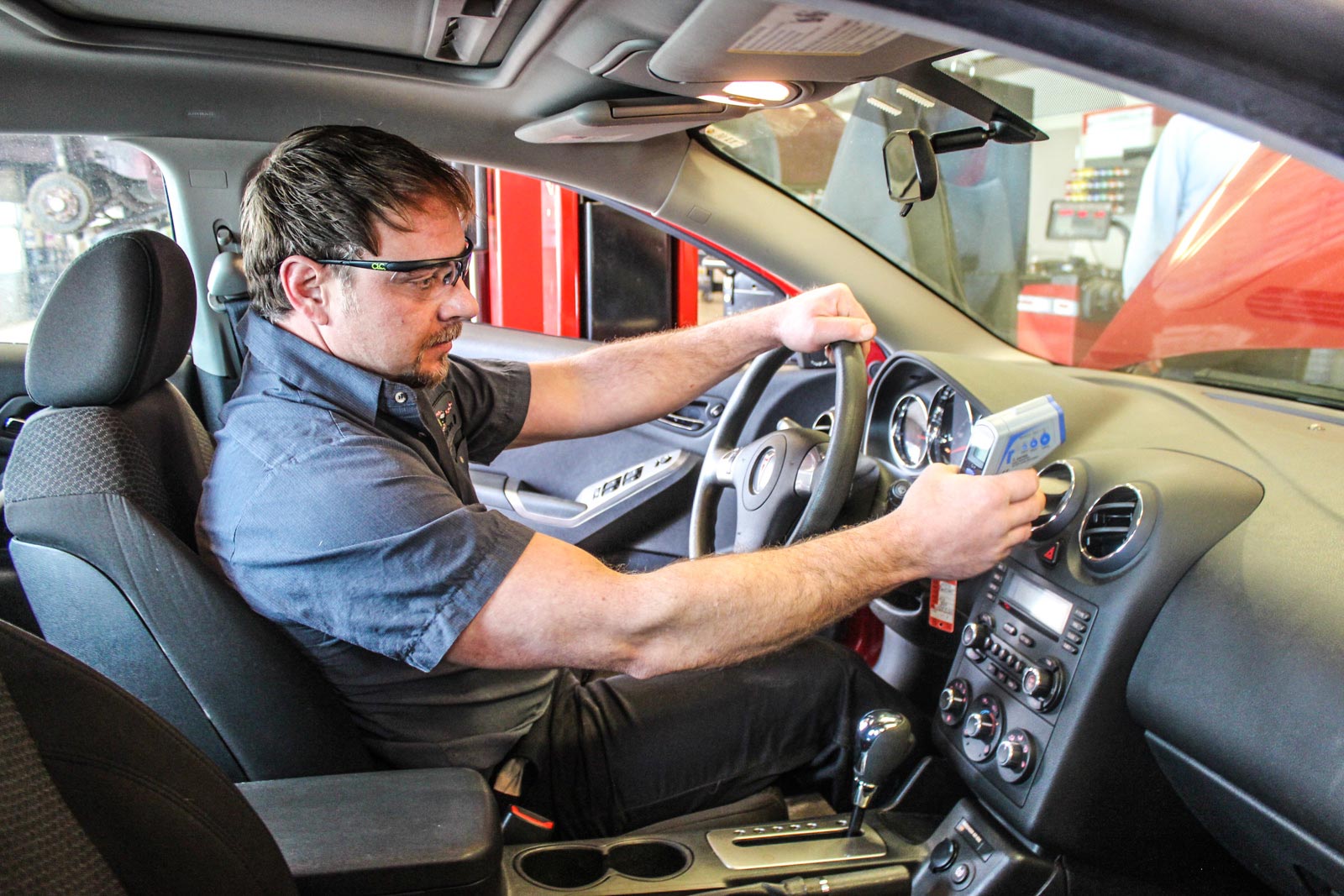 Technician inspecting a vehicle's AC system at Rad Air Complete Car Care