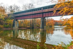 The Bridge of Dreams is a covered Bridge spanning over Mohican river in a fall season | Rad Air Complete Car Care The Bridge of Dreams is a covered Bridge spanning over Mohican river in a fall season