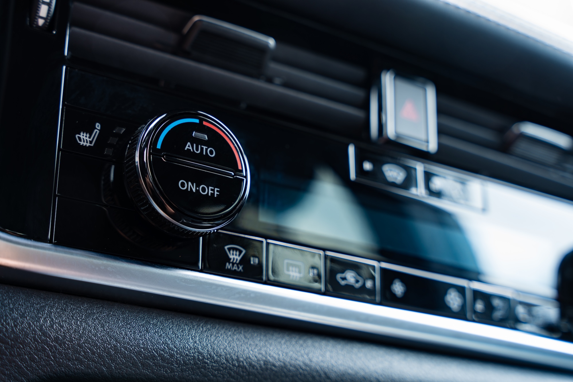 Driver adjusting the air conditioning controls in a car dashboard